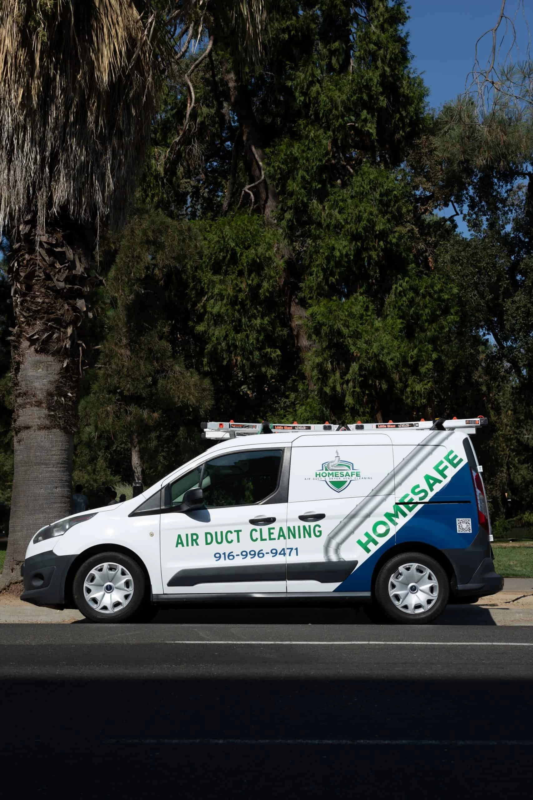 A white van with the text "AIR DUCT CLEANING" and "HOMESAFE" is parked on the street in front of a cluster of palm trees. Specializing in HVAC cleaning, the van displays a phone number: 916-584-9367, along with a company logo.